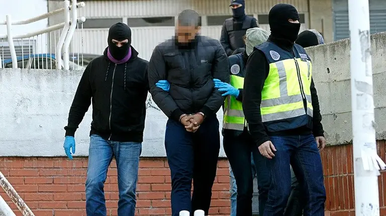 Agentes de las Fuerzas y Cuerpos de Seguridad del Estado con uno de los 18 jóvenes detenidos hoy en la operación contra algunos miembros de Indar Gorri, grupo de aficionados de Osasuna, se dirigen al registro efectuado en la sede de este grupo, hoy en Pamplona. EFE/Ivan Aguinaga