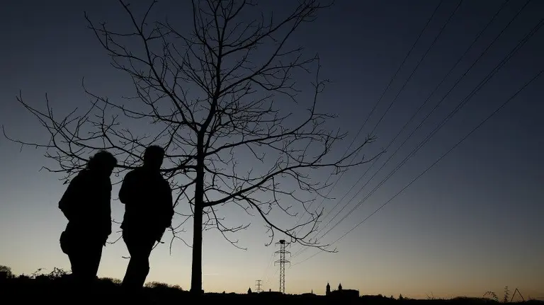 Tiempo, varias personas caminan junto al río Arga durante el atardecer en Pamplona. EFE.