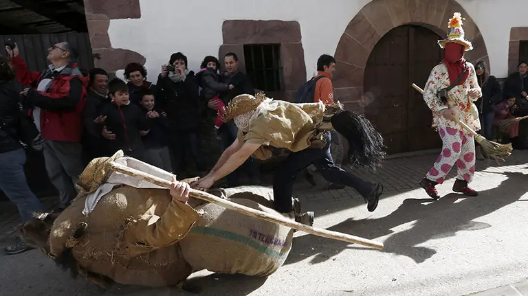 GRA465. LANTZ (NAVARRA), 08/02/2016.- Momento del carnaval rural de gran tradición que se celebra hoy en la localidad navarra de Lantz, en el que las fuerzas del mal y del bien se enfrentan en una batalla simbólica en la que la sed de justicia moviliza las iras populares. El desfile lo conforman personajes como Ziripot (en el suelo), hombre bonachón hecho de sacos rellenos de helechos, que apenas puede mantenerse en pie y al que persigue el Zaldiko (c), caballo bravío que arremete contra él hasta tirarlo al suelo y que junto con los Txatxos (bailando), armados con palos y escobas, gritan mientras hostigan a los asistentes y preceden a Miel Otxin , un malvado bandido al que apresan y queman en la hoguera. EFE/Jesús Diges