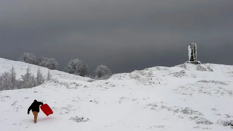 Una persona con su trineo en el Alto de Ibañeta, (Navarra), que hoy ha amanecido nevado debido a la progresiva bajada de la cota de nieve, y que ha hecho que durante la noche se movilicen máquinas quitanieves de forma preventiva. EFE/VILLAR LÓPEZ