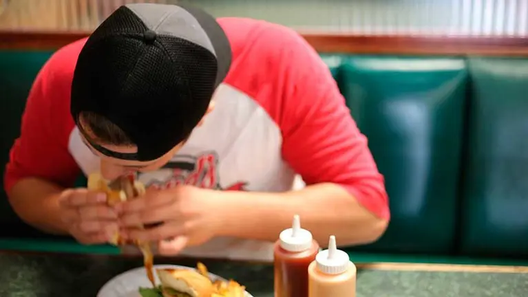 Un estudiante comiendo comida rápida.