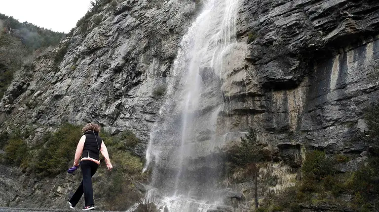 GRA228. BELAGOA (NAVARRA), 20/03/2016.- Una mujer camina por la N-137 junto a una cascada de agua producto del deshielo tras las intensas nevadas de los últimos días y por la subida de las temperaturas, en el primer día de la primavera que deja hoy en el norte de Navarra precipitaciones debiles con temperaturas que oscilan entre 1 y 11 grados. La primavera que ha comenzado esta mañana, a las 5:30 horas, se presenta en la comunidad foral "más cálida de lo normal" en cuanto a temperaturas y "normal" en cuanto a precipitaciones. EFE/Jesús Diges