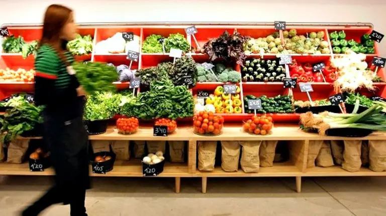 Una mujer en la sección de verduras del mercado.