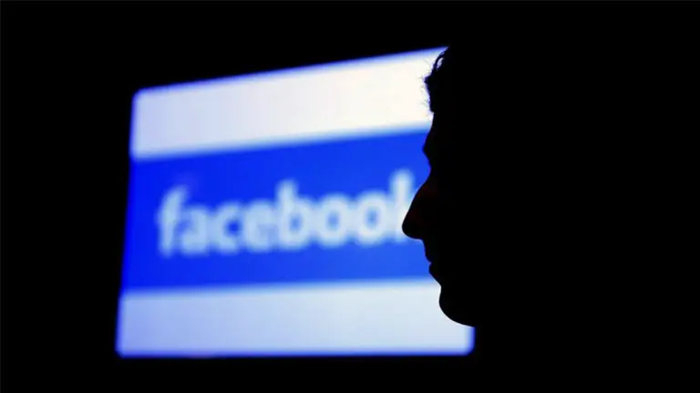 Una persona pasa junto al logotipo de la red social Facebook.