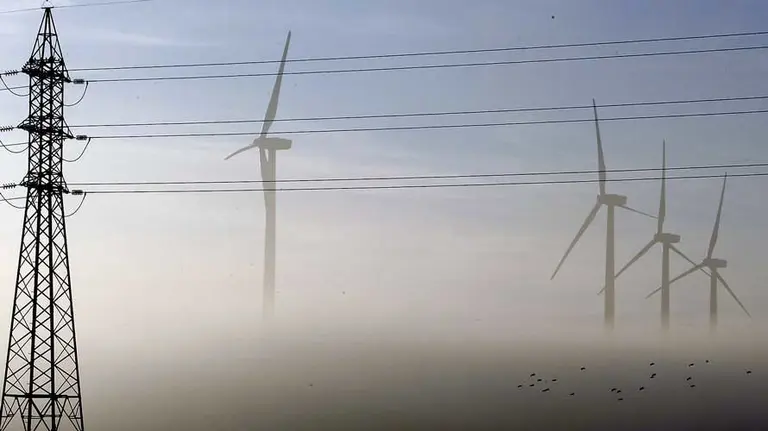Molinos de viento y torres electricas difuminados por la niebla.