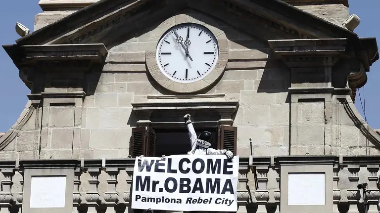 Una persona vestida con traje de astronauta coloca una pancarta dando la bienvenida al presidente de EE.UU Barak Obama en el balcon del Ayuntamiento, antes de lanzar el tradicional chupinazo, que ha abierto a las doce del mediodía las Fiestas de San Fermín 2016, en las que la ciudad se convierte durante nueve días en una marea blanca y roja que arropa los encierros de los toros y los conciertos musicales. EFE/Jesús Diges