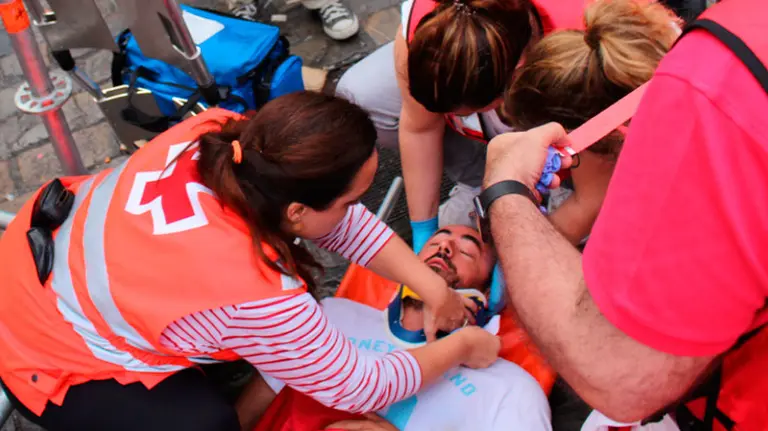 Los sanitarios atienden a uno de los mozos que ha sufrido un traumatismo craneal tras una voltereta. S. REDíN