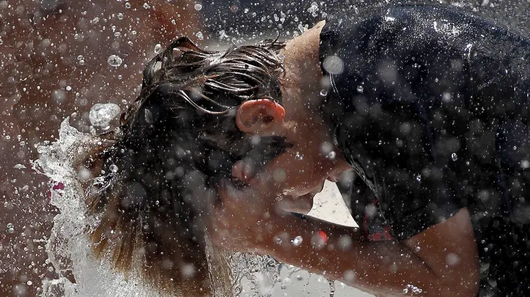 Un joven se refresca en una fuente de Pamplona. EFE/Villar López
