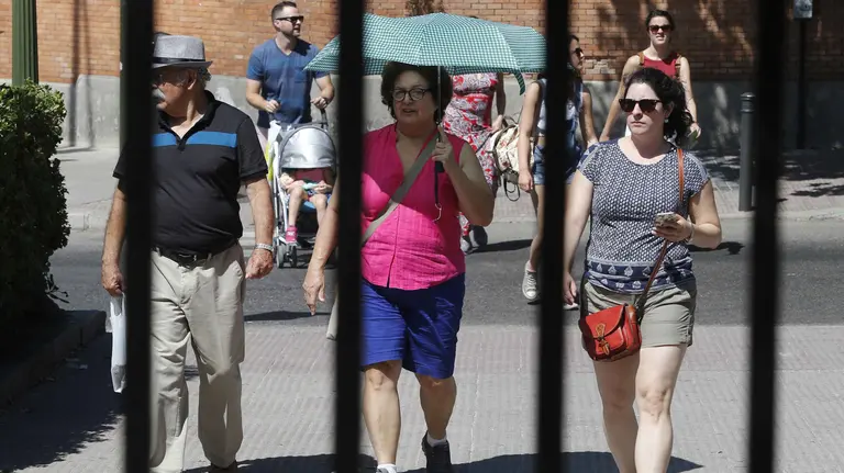 En la imagen, varios viandantes se protegen del sol con gorros y paraguas. EFE/Mariscal