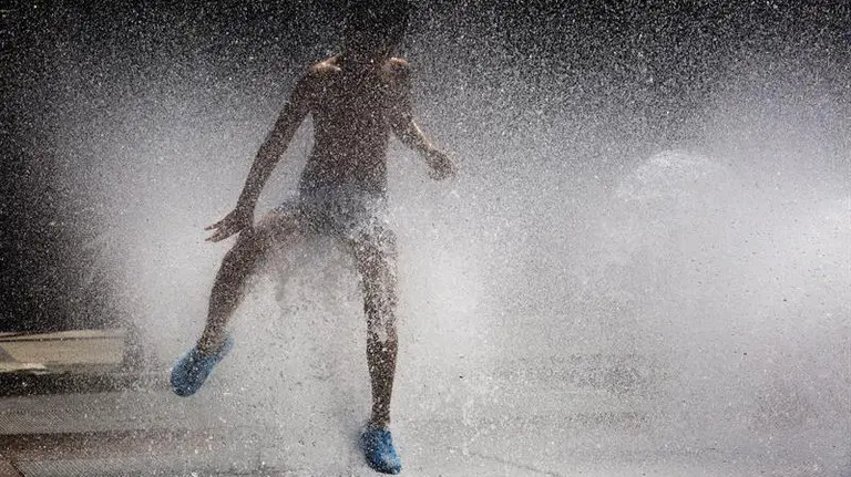 Un niño se divierte con el agua de una fuente de Pamplona. EFE/Villar López