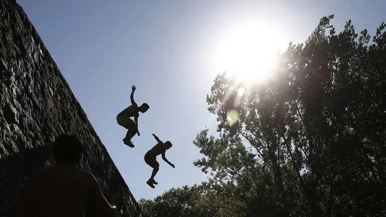 Varios jóvenes se lanzan desde el puente de la Magdalena al rio Arga bajo un intenso sol. Las imágenes del tiempo marcado por el calor vivido en Pamplona. EFE/Jesús Diges
