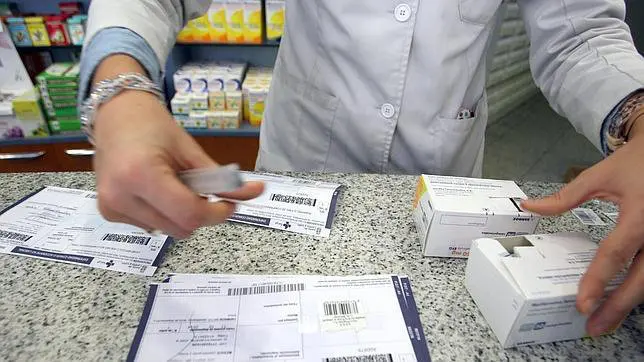 Un farmacéutico trabaja con varias recetas en papel Imagen de archivo