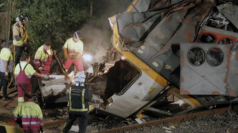 Los bomberos despiezan la cabina del tren de la compañía Comboios de Portugal que cubría la línea entre Vigo y Oporto, que descarriló ayer en la localidad pontevedresa de O Porriño causando cuatro muerto y casi medio centenar de heridos, esta madrugada en Porriño. EFE/Lavandeira jr.