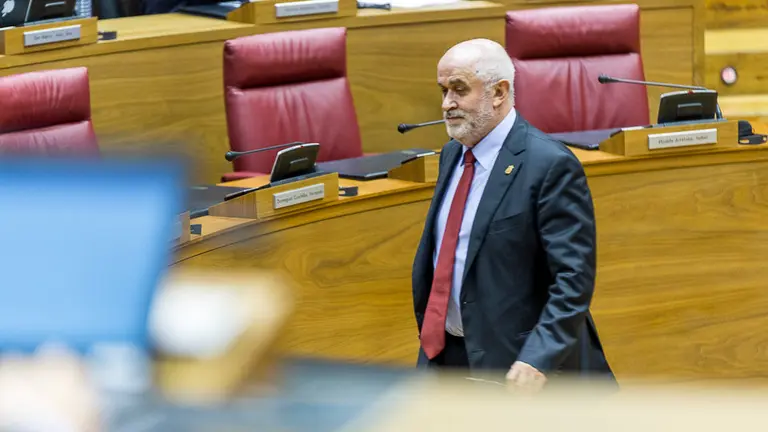 El consejero de Educación, José Luis Mendoza, vuelve a su asiento tras intervenir en el pleno del Parlamento de Navarra (1). IÑIGO ALZUGARAY