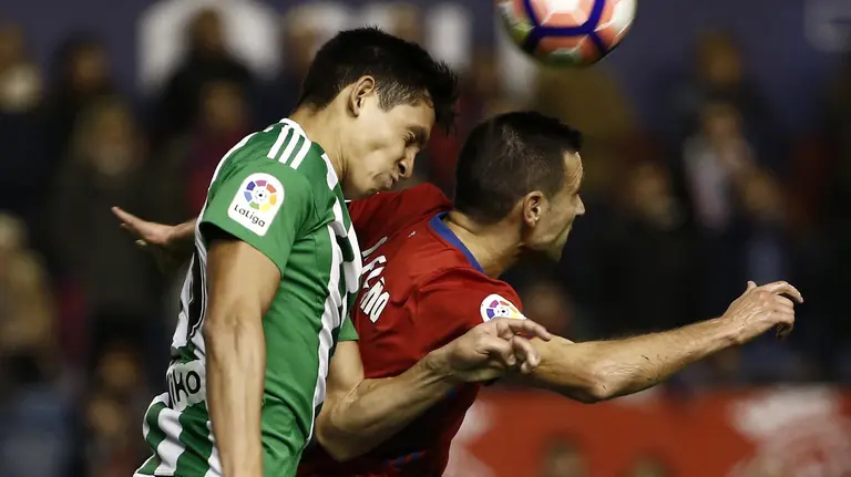 El defensa de Osasuna Miguel Flaño (d) cabecea un balón ante el argentino Germán Pezzella, del Real Betis, durante el partido de Liga en Primera División disputado en el estadio de El Sadar, en Pamplona. EFE/Jesús Diges