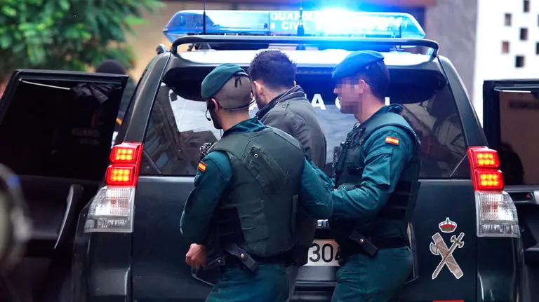 Agentes de la Guardia Civil trasladan a un marroquí detenido por supuestos delitos de enaltecimiento y difusión de propaganda del Daesh. EFE.