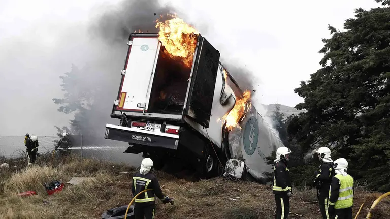 Varios bomberos intentan sofocar el incendio un camión frigorifico tras el accidente ocurrido en la AP 15 en sentido sur después de chocar contra un vehículo militar. EFE/Jesús Diges