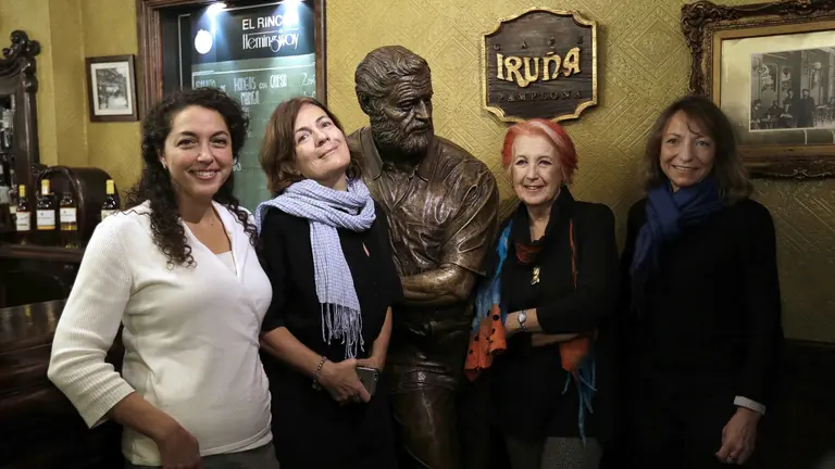 Cuatro mujeres periodistas que ejercen como corresponsales internacionales, la americana Pamela Rolfe, la francesa Cécile Thibaud, la española Rosa María Calaf y la italiana Paola Vecchio, posan junto a una escultura del escritor y periodista Ernest Hemingway, en el Café Iruña de Pamplona en el ciclo "Recordando a Hemingway". EFE/Villar López
