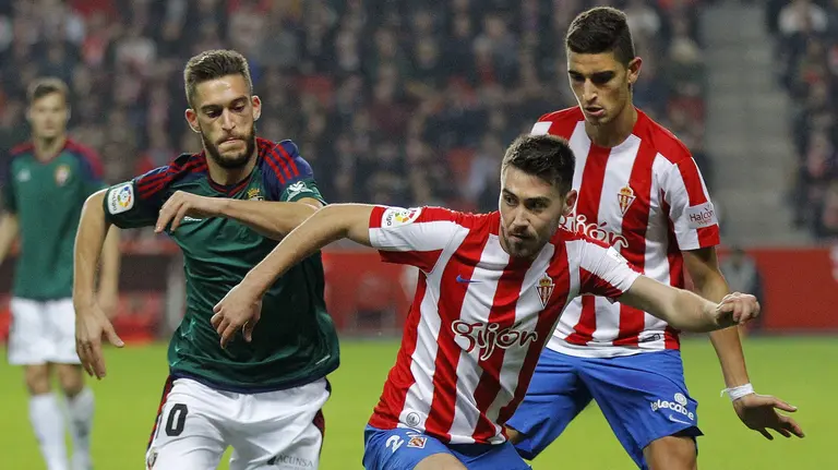 El centrocampista del Sporting Moisés Gómez (c) con el balón ante el centrocampista del Osasuna Roberto Torres en el estadio de El Molinón. EFE/Alberto Morante