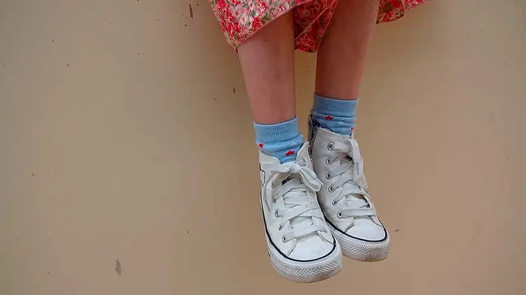 Niña con zapatillas blancas.