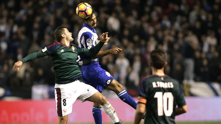 El centrocampista costarricenes del Deportivo Celso Borges disputa un balón con el centrocampista serbio Goran Causic de Osasuna. EFE/Kiko Delgado