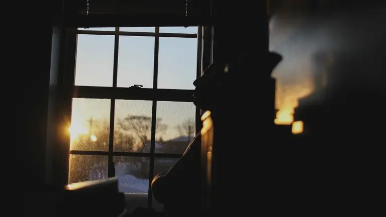 Un hombre apoyado cerca de la ventana en una imagen de recurso. ARCHIVO