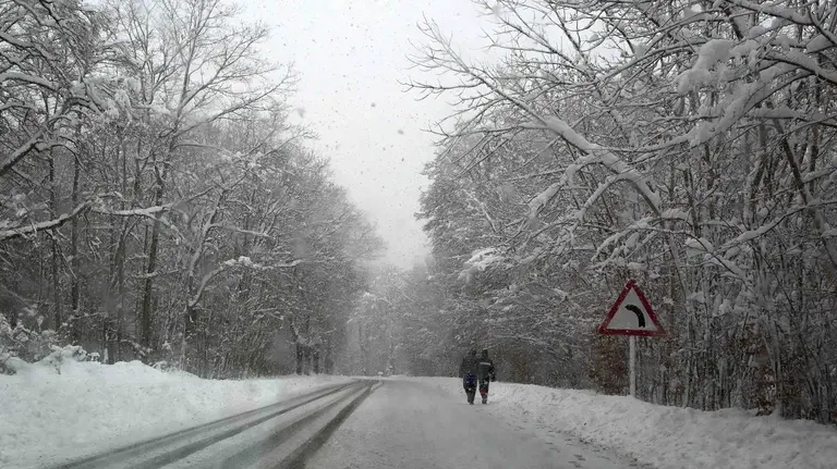 Dos personas caminan por la N-135 en el término de Roncesvalles (Navarra), comunidad donde continúa el temporal de nieve con esperoses que alcanzan los 50cm de nieve. EFE/Villar López