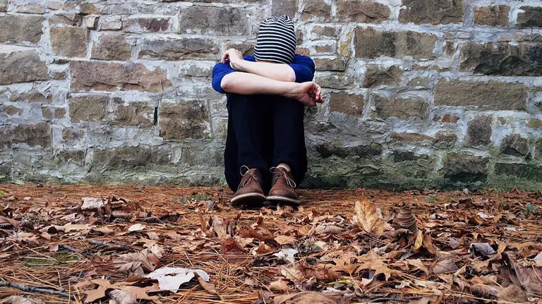 Un joven solitario se lamenta junto a un muro de piedra durante un día de mal tiempo ARCHIVO