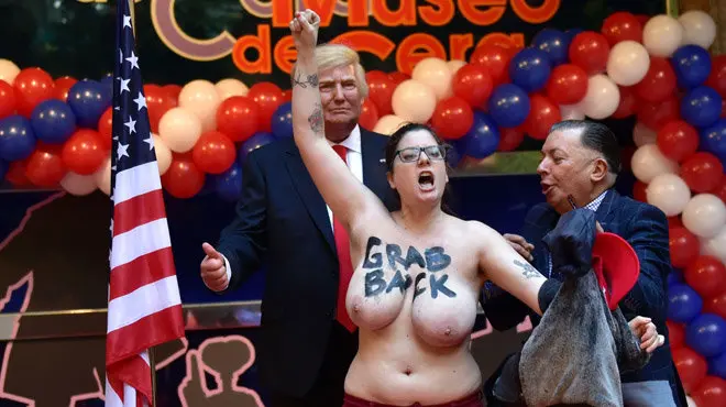 Madrid's Wax Museum director Gonzalo Presa (R) tries to protect the wax statue of US President-elect Donald Trump from a topless Femen activist protesting in Madrid on January 17, 2017. / AFP PHOTO / GERARD JULIEN