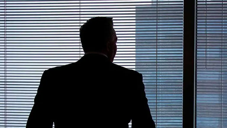 Hombre mirando por la ventana desde una oficina. ARCHIVO