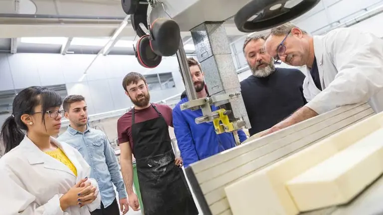 Varios estudiantes atienden las explicaciones de Ángel Jaraba (dcha.) y Carmelo Puyo (a su dcha.) en uno de los talleres de rotomoldeo.