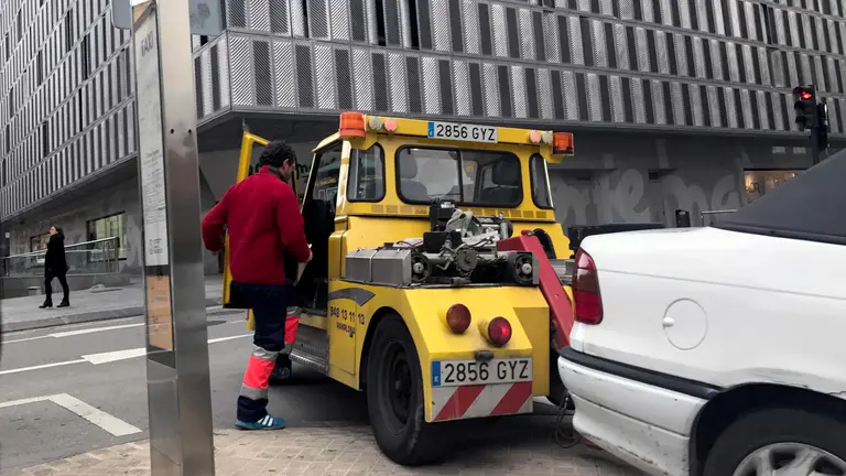 Una grúa retira un vehículo en la calle Estella de Pamplona.