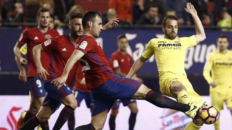 El delantero del Villarreal Roberto Soldado (d) lucha el balón con el serbio Goran Causic, defensa de Osasuna, durante el partido correspondiente a la 25ª jornada de Liga en Primera División que se disputa esta noche en el estadio de El Sadar, en Pamplona. EFE/Jesus Diges