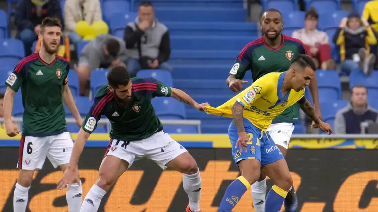 El centrocampista de la UD Las Palmas Roque Mesa (d) es agarrado por Jaime, de Osasuna, durante el partido de Liga en Primera División disputado esta tarde en el estadio de Gran Canaria, de Las Palmas. EFE/Ángel Medina