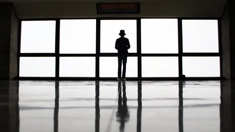 Un hombre mira por una ventana en soledad