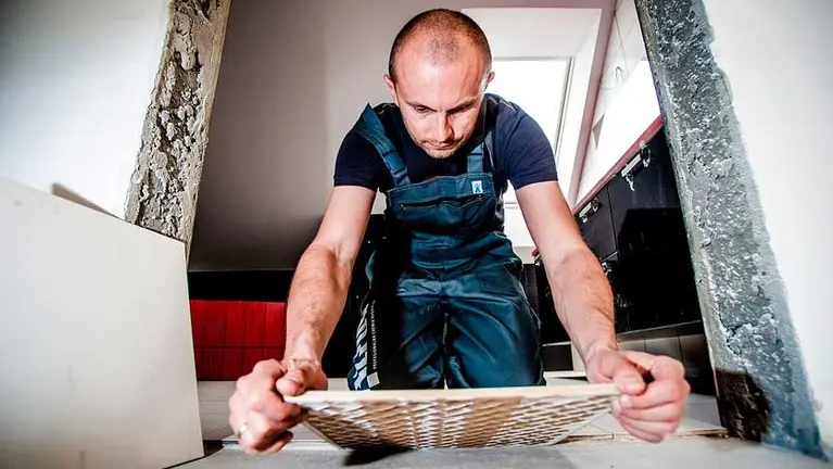 Trabajador alicatando un baño. ARCHIVO