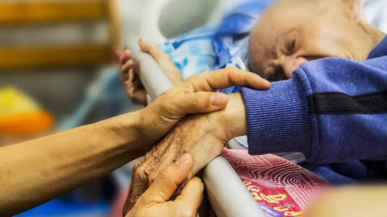 Una persona cuida a un anciano que se encuentra convaleciente en su cama. ARCHIVO