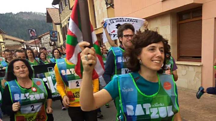 La teniente alcalde de Pamplona corre en la Korrika entre carteles de presos terroristas y portando una ikurriña.