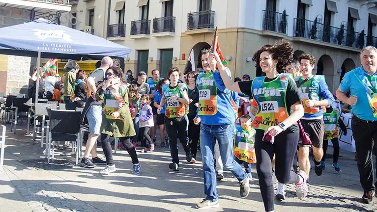 Itziar Gómez y Mikel Armendáriz (Geroa Bai-PNV) corren con la ikurriña durante la Korrika en Pamplona.jpg