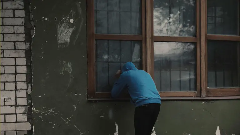 Un ladrón mira por la ventana para asegurarse de que la vivienda permanece vacía. ARCHIVO.