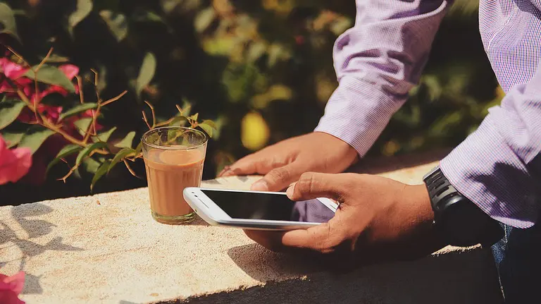 Imagen de un hombre manejando su smartphone mientras toma un caf&eacute; ARCHIVO