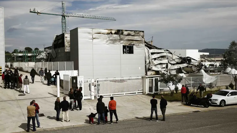 Trabajadores de la empresa Poliéster Resitex, en Esquiroz, observan desde el exterior el estado que el que han quedado las naves tras el incendio que la ha dejado complemente destruida. EFE/Jesús Diges