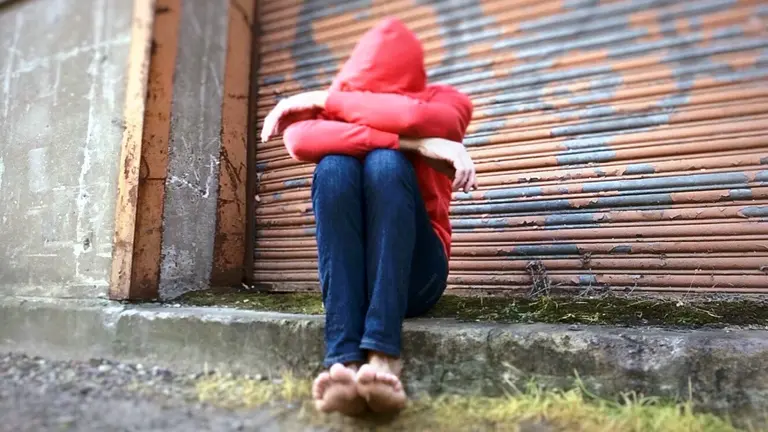 Una mujer se protege de una agresión en la calle.