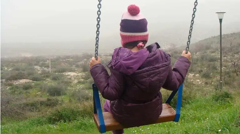 Una niña juega en un columpio en el campo. ARCHIVO