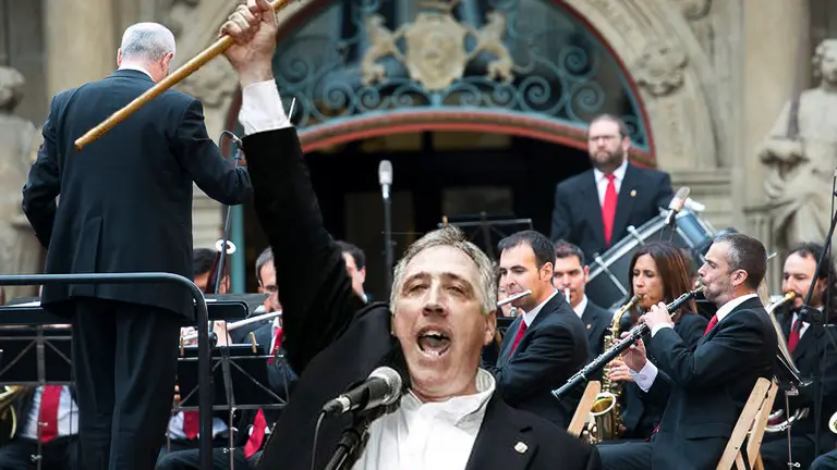 Imagen de un concierto de La Pamplonesa en la Plaza Consistorial junto a la fotografía de Joseba Asirón al tomar el cargo como alcalde de Pamplona. NAVARRA.COM