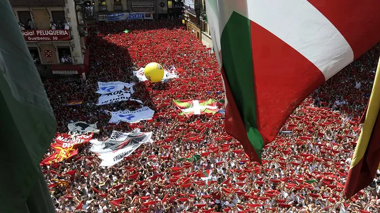 GRA084. PAMPLONA, 31/07/2014.- Miles de personas lanzan el tradicional "pañuelico" rojo en la Plaza del Ayuntamiento de Pamplona durante el lanzamiento del Chupinazo, con el que a las doce del mediodía dan comienzo las fiestas de San Fermín. EFE/Villar López