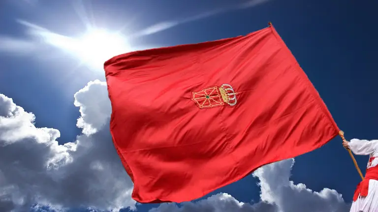 Foromontaje de un hombre enarbolando la bandera de Navarra bajo el sol tras despejarse un nubarrón