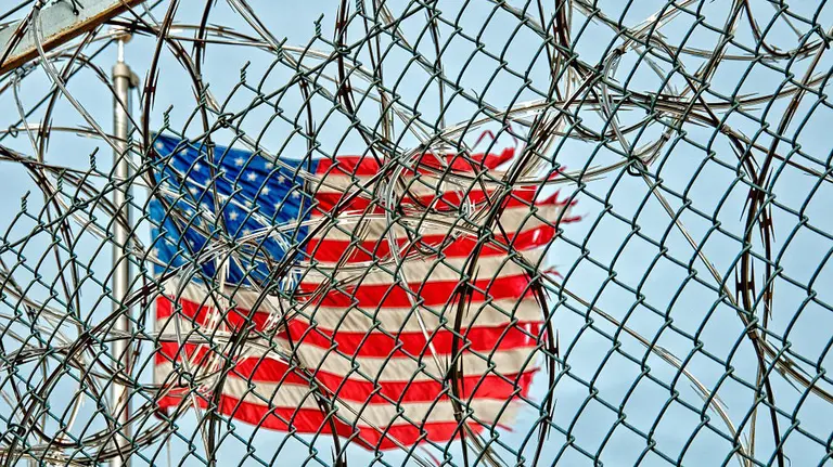 Imagen de una bandera de Estados Unidos ondeando tras el perímetro de seguridad de una prisión ARCHIVO