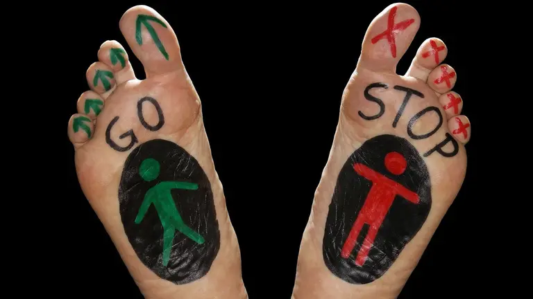 Dos pies ilustrados con los clásicos dibujos de un paso de peatones con semáfoto