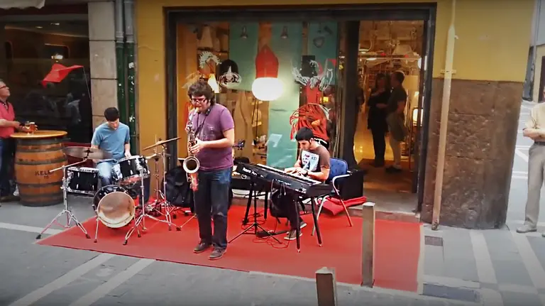 Un grupo de músicos da un espectáculo junto a un comercio